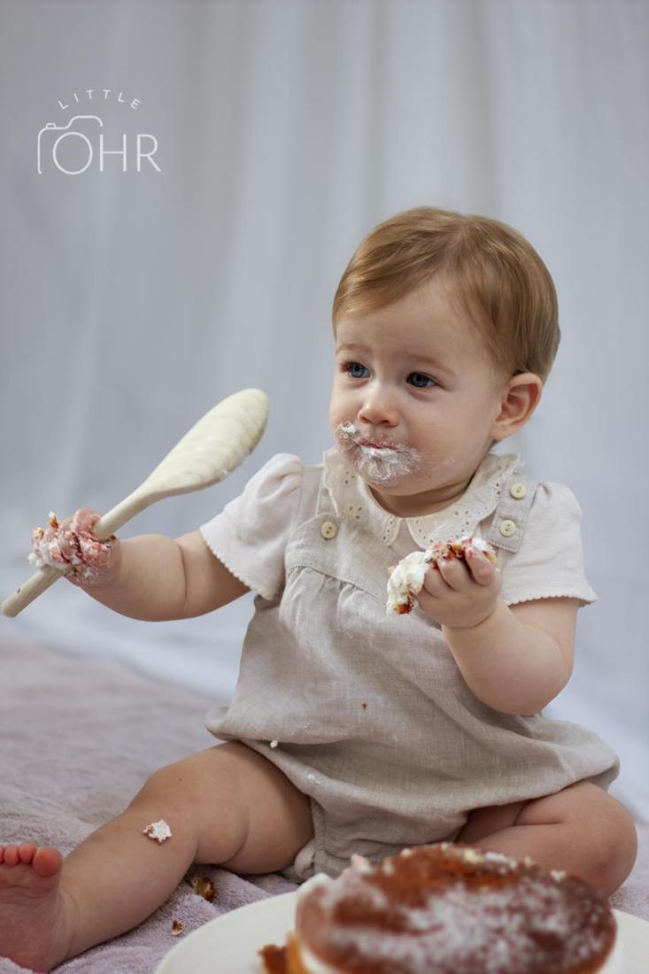 Baby waving a wooden spoon covered in cream