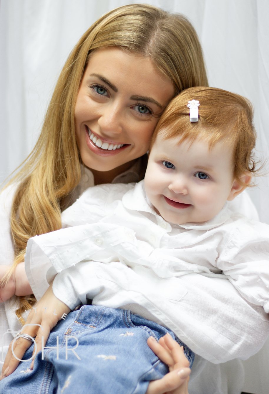 Mum cuddling her smiling baby girl in the studio