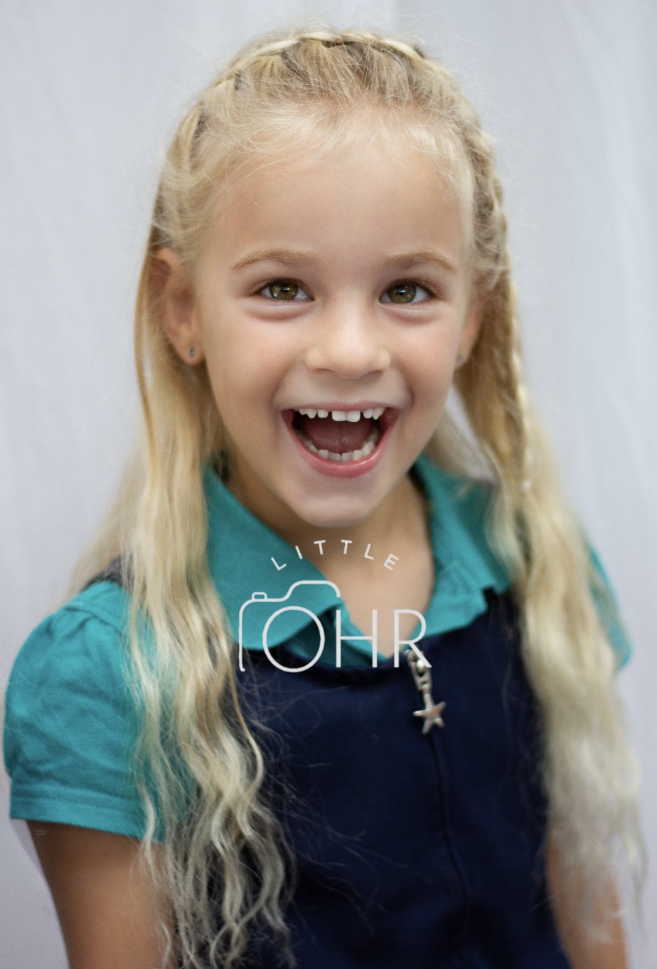Laughing girl with long blonde hair in a teal school polo shirt